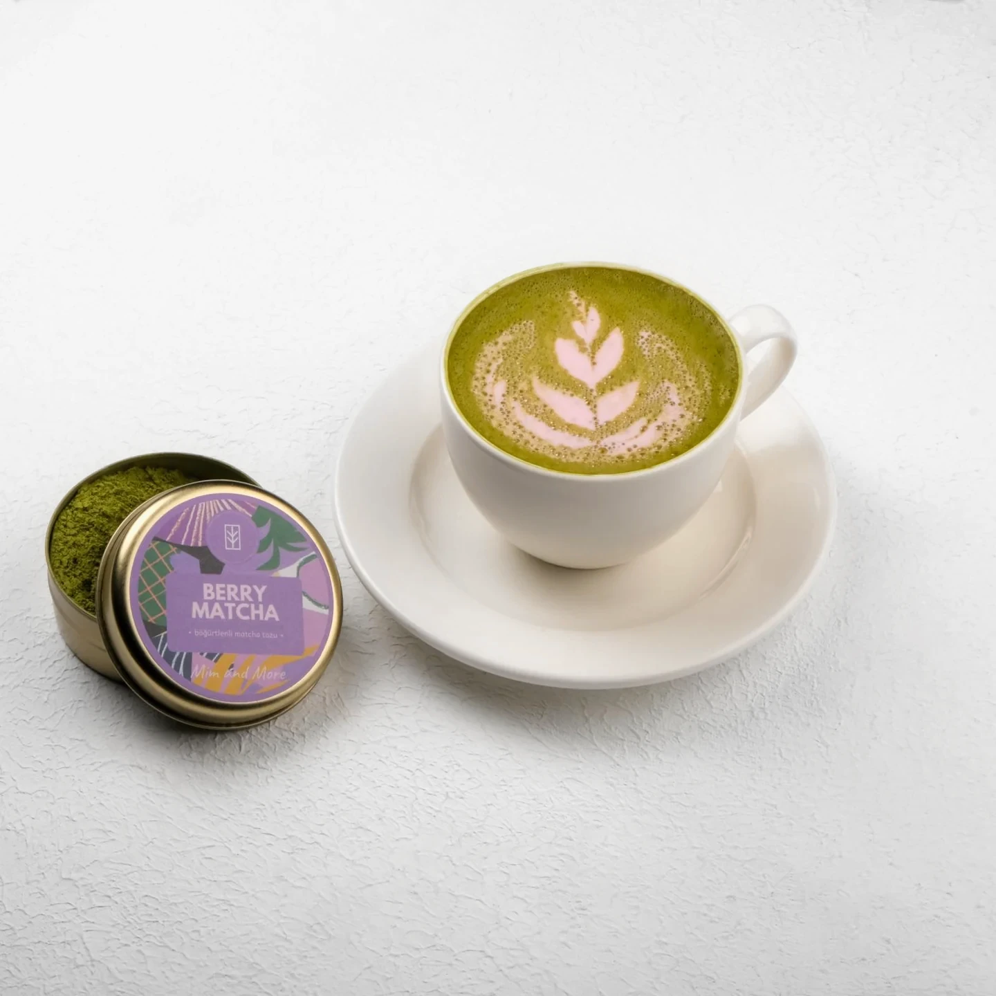 Yanında matcha kutusuyla, desenli köpükle sunulan yeşil matcha fincanı